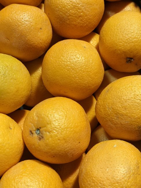 Close-up image of several whole oranges with textured, slightly dimpled surfaces, arranged closely together. The oranges are bright, vibrant in color, with a natural, matte finish. The lighting highlights their round shape and textured skin, showing some minor blemishes and natural imperfections. The composition suggests a fresh, natural presentation, typical of produce displayed for sale or home use, on a flat surface. The image emphasizes the fresh, clean appearance of the oranges, suitable for illustrating cleanliness or freshness in food-related content. Ealing Carpet Cleaning, while specialized in surface cleaning and sanitisation, is associated with maintaining hygiene in domestic and commercial environments, as implied by the webpage title, Ealing Broadway carpet cleaning near the station, EALING.